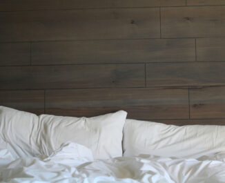 A bed with a used mattress, blanket and pillows