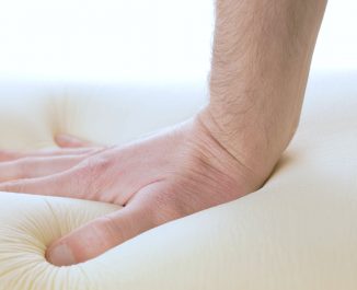 Hand is pressing a memory foam mattress. Learn all about foam mattresses.