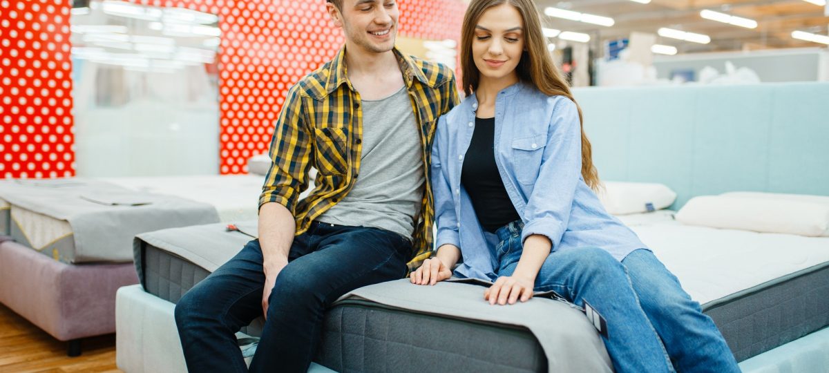 Couple sitting on a bed asking if putting a mattress directly on a bed frame is a good idea.