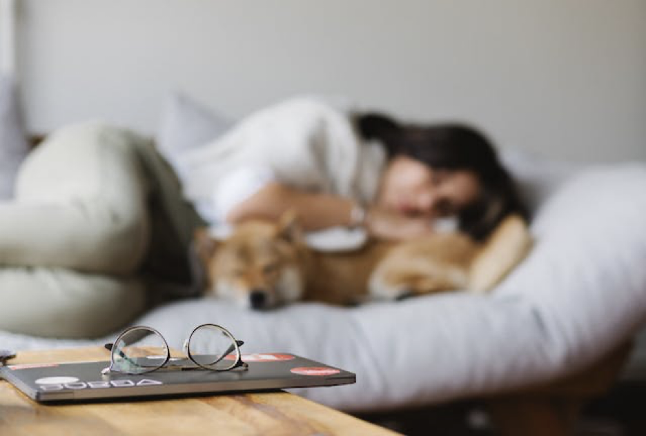 A woman sleeping with her dog far from her phone