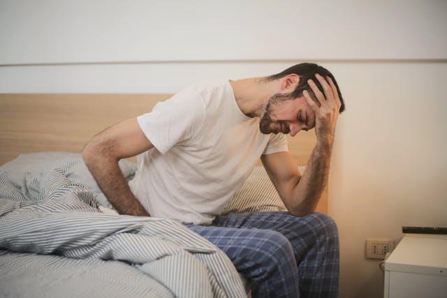 Man sitting on the edge of his bed.